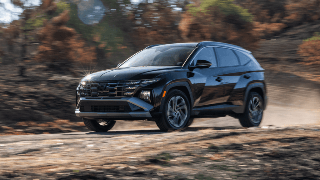 2025 Hyundai Tucson Hybrid driving off-road on a rugged trail with dust and terrain in the background.