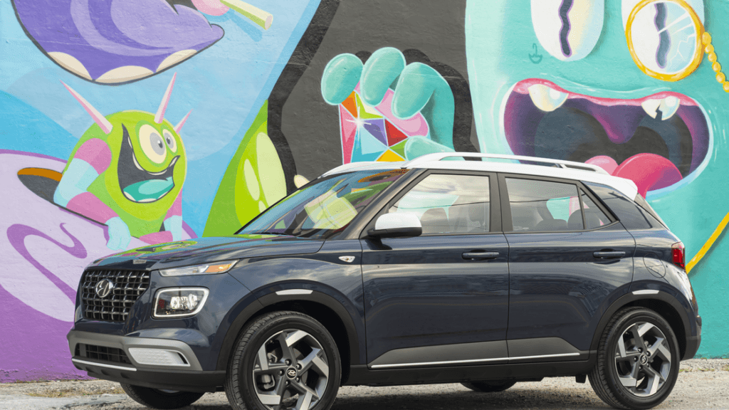 2025 Hyundai Venue parked by colorful mural showcasing compact SUV design in dark blue finish.