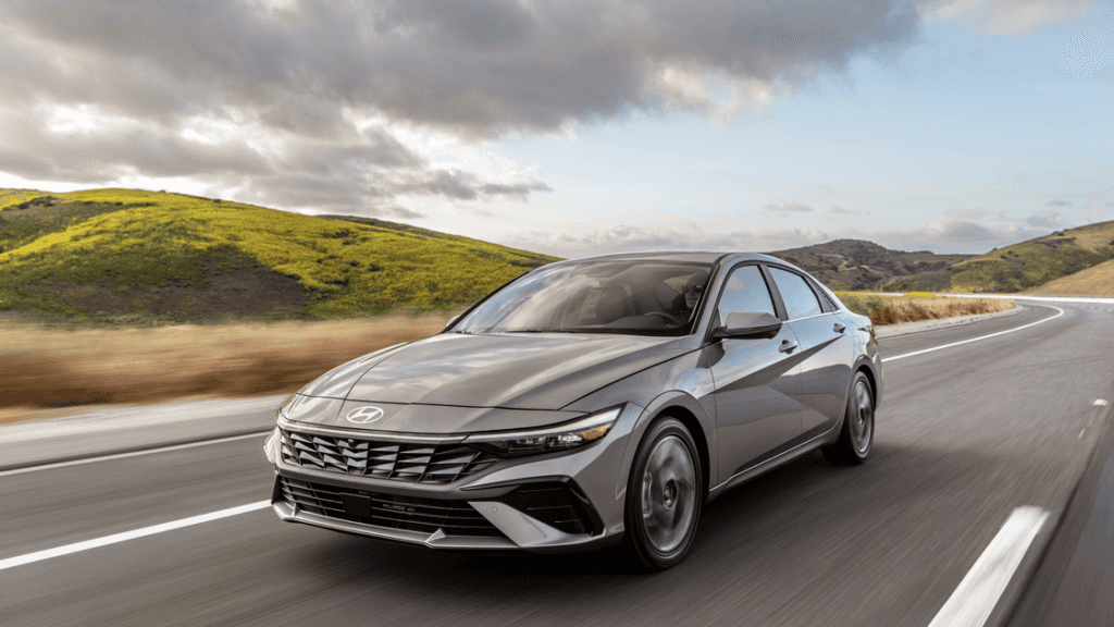 2026 Hyundai Elantra sedan driving on open highway with sleek exterior styling and modern LED lighting.