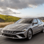 2026 Hyundai Elantra sedan driving on open highway with sleek exterior styling and modern LED lighting.