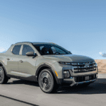 2026 Hyundai Santa Cruz sport adventure truck driving on desert road with bold grille and wheels.