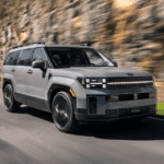 2026 Hyundai Santa Fe SUV driving on scenic road featuring boxy design and modern lighting.