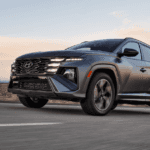 2026 Hyundai Tucson SUV driving at dusk showcasing dynamic body lines and aggressive front fascia.