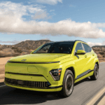 2026 Hyundai Kona Electric SUV front three quarter view in green driving on desert highway.