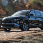 2026 Hyundai Tucson Hybrid compact SUV front three quarter view driving on gravel trail.
