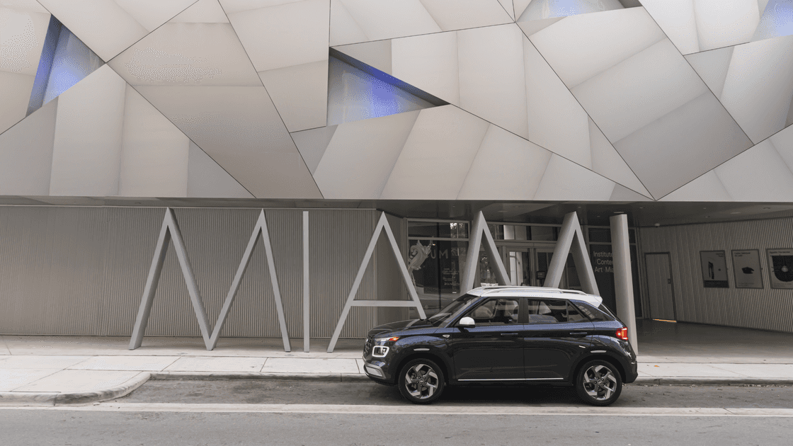 2026 Hyundai Venue subcompact SUV side view parked in front of modern art museum.