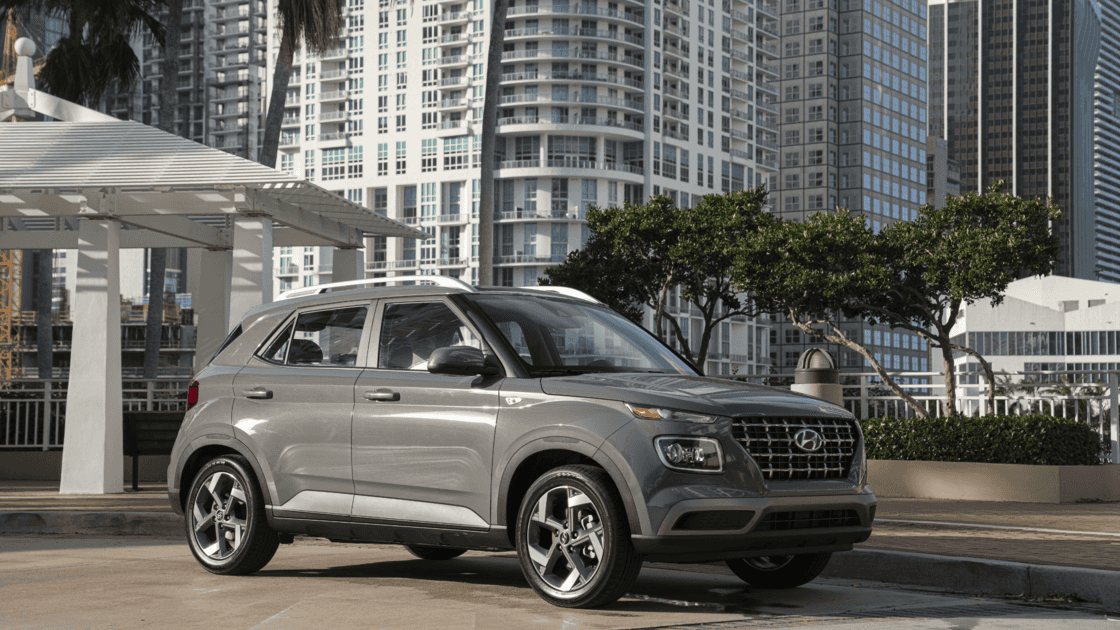 Exterior view of the 2026 Hyundai Venue parked in an urban setting, highlighting compact SUV proportions and modern grille styling.