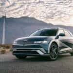 2026 Hyundai IONIQ 5 electric SUV parked near wind turbines, highlighting modern EV design and clean energy styling.