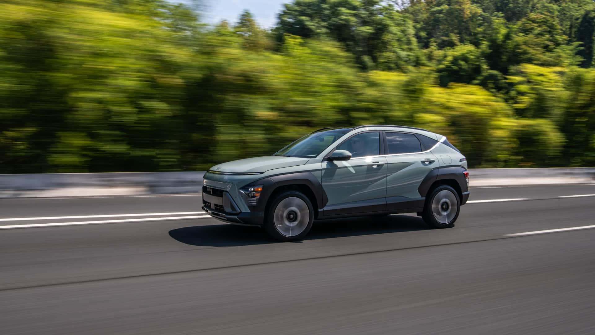 2026 Hyundai Kona front three quarter view driving on scenic countryside road.
