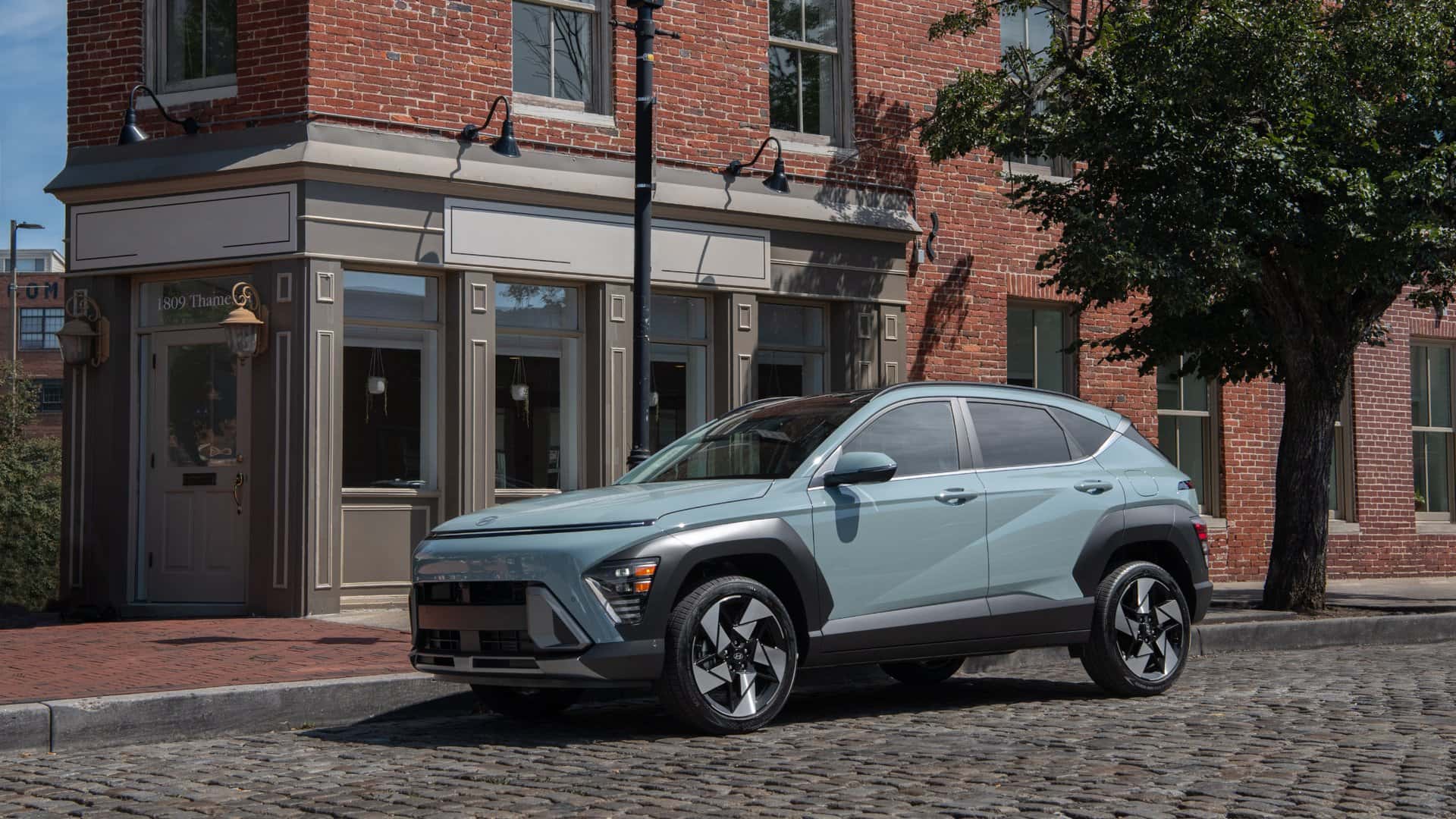 2026 Hyundai Kona compact SUV front three quarter view parked on city street highlighting updated exterior styling and LED daytime running lights.