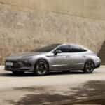 2026 Hyundai Sonata sedan driving on city road highlighting sleek body lines LED lighting and modern front fascia design.