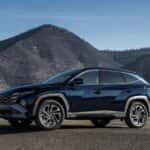 2026 Hyundai Tucson Hybrid SUV side profile in mountainous landscape showcasing hybrid capability rugged styling and alloy wheels.