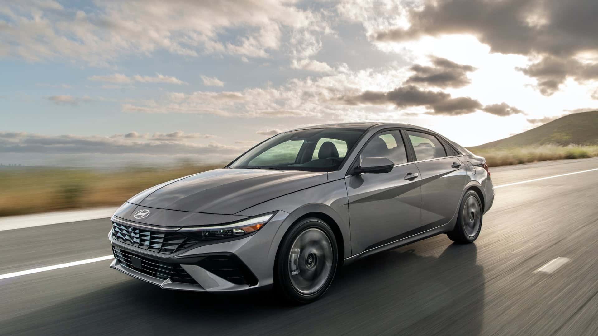 2026 Hyundai Elantra sedan driving on an open road in front three quarter view.
