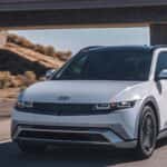 2026 Hyundai IONIQ 5 electric SUV driving on a desert road in front three quarter view.
