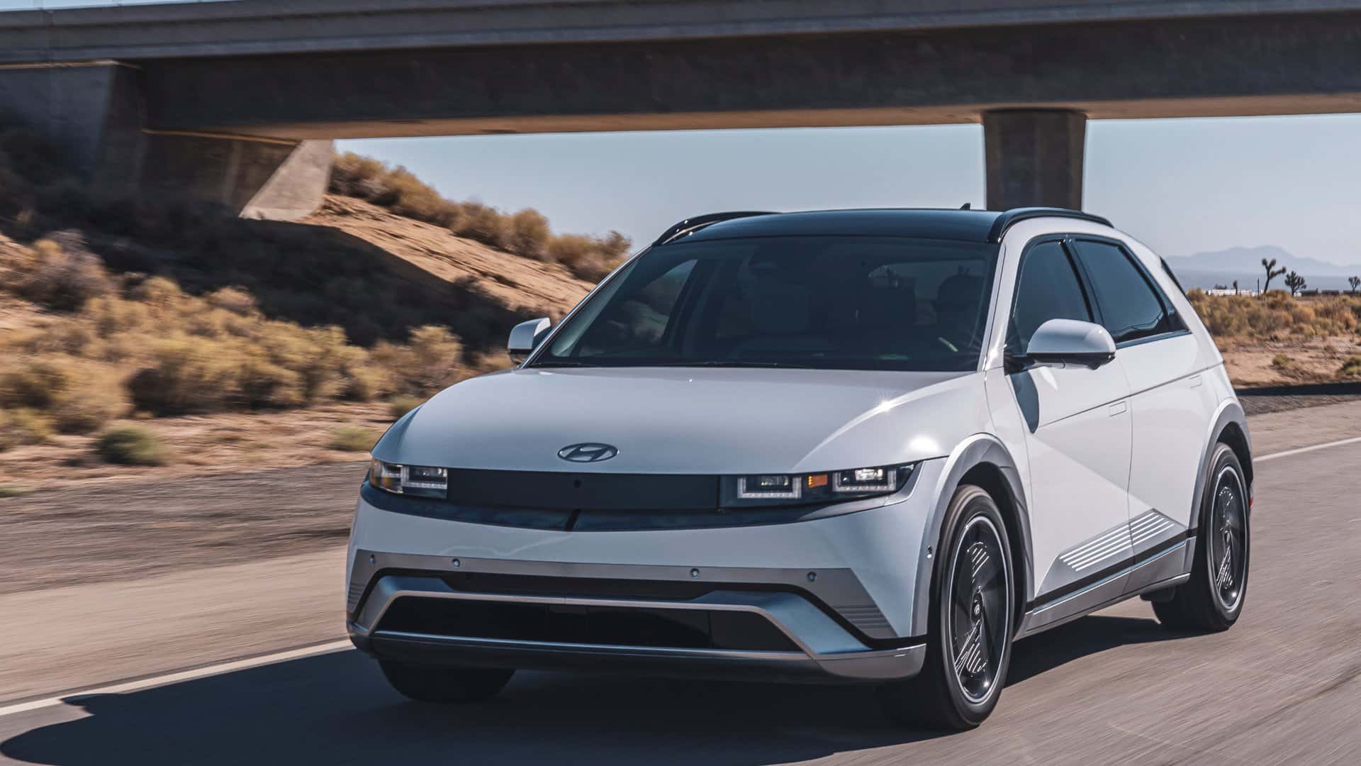 2026 Hyundai IONIQ 5 electric SUV driving on a desert road in front three quarter view.