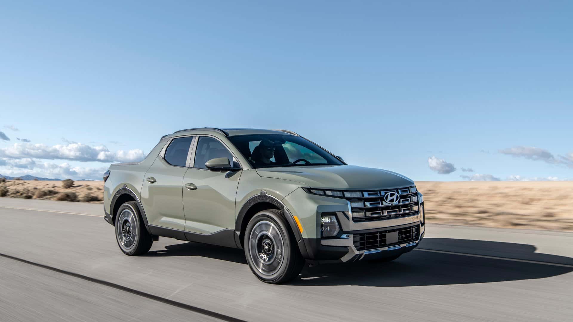 2026 Hyundai Santa Cruz pickup truck driving on a highway in front three quarter view.