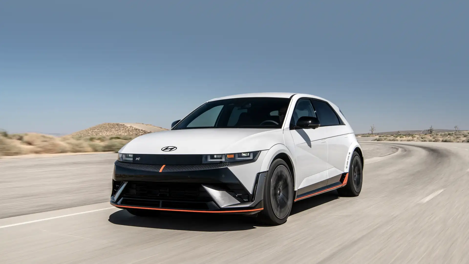 2026 Hyundai IONIQ 5 N white electric SUV driving on desert road with orange accent trim.