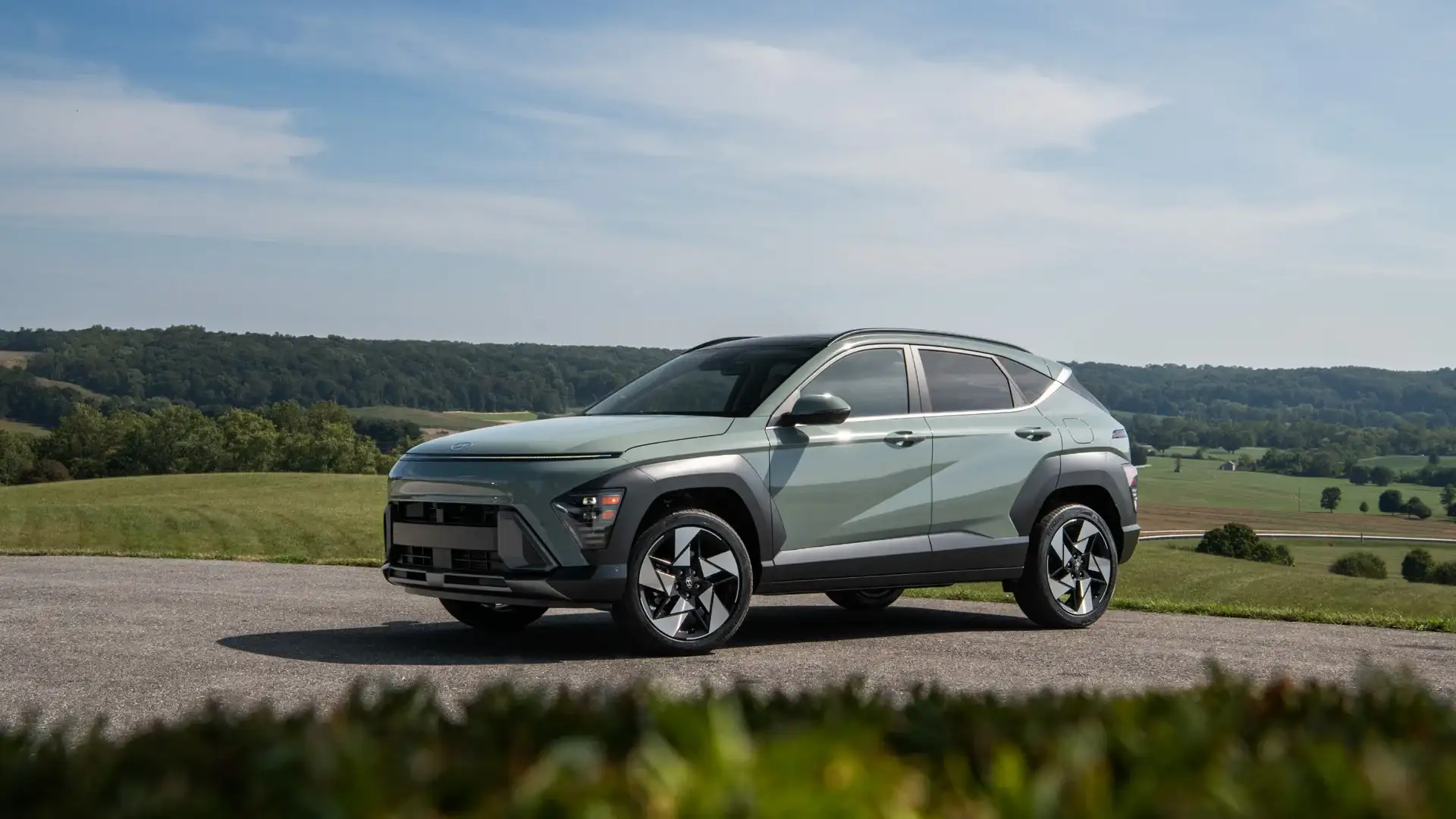 2026 Hyundai Kona green compact SUV parked on scenic hillside road with modern exterior styling.