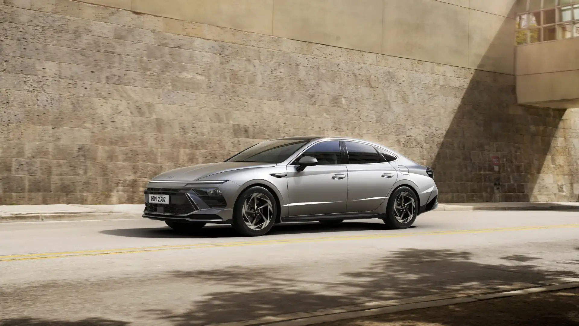 2026 Hyundai Sonata silver sedan parked under modern concrete structure with coastal background.