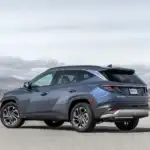 2026 Hyundai Tucson blue SUV shown from rear angle in desert landscape with angular body styling.