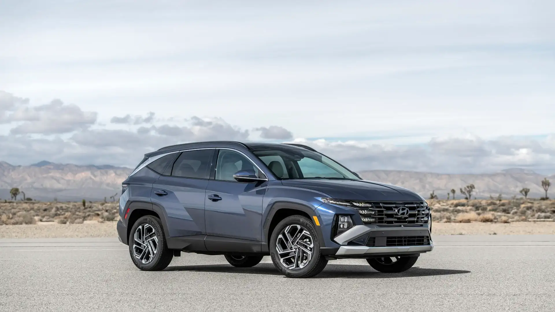 2026 Hyundai Tucson blue SUV parked in desert landscape with bold grille and angular exterior design.