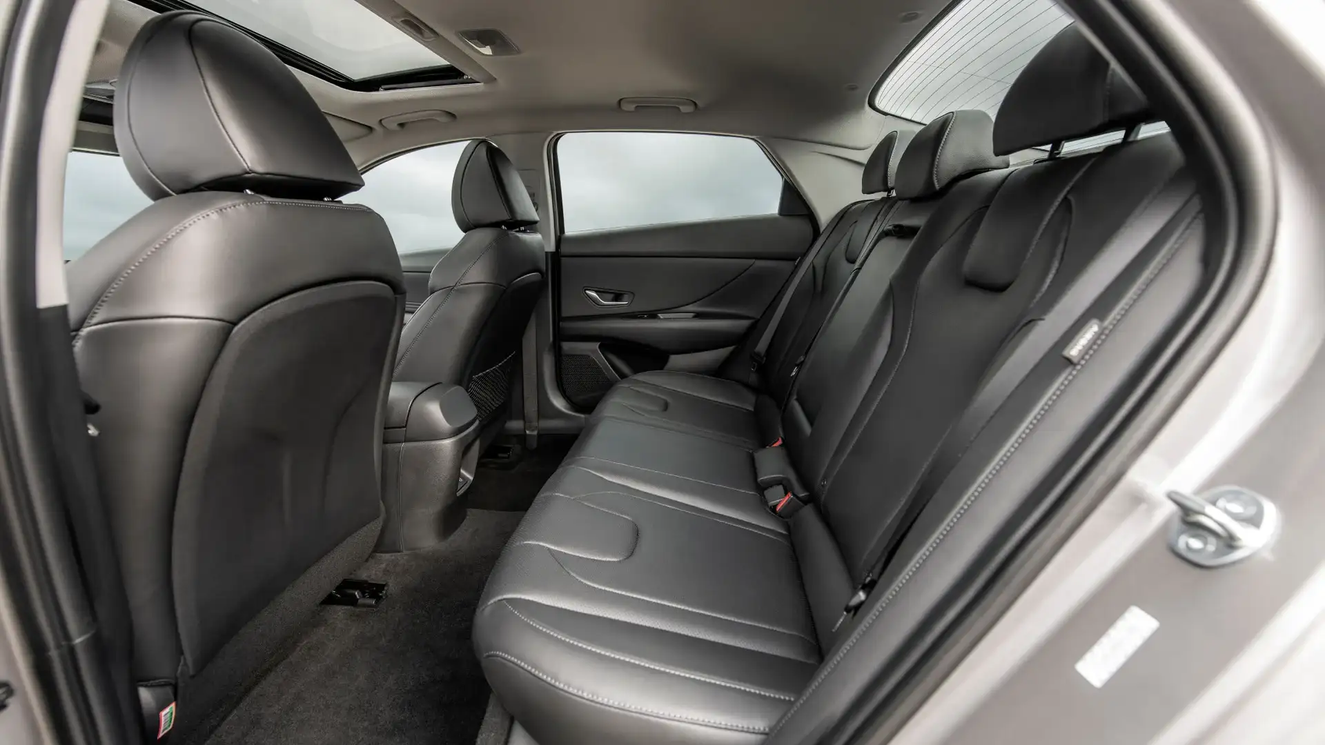 2026 Hyundai Elantra rear seating area with black upholstery, seatbelts, and sunroof view.