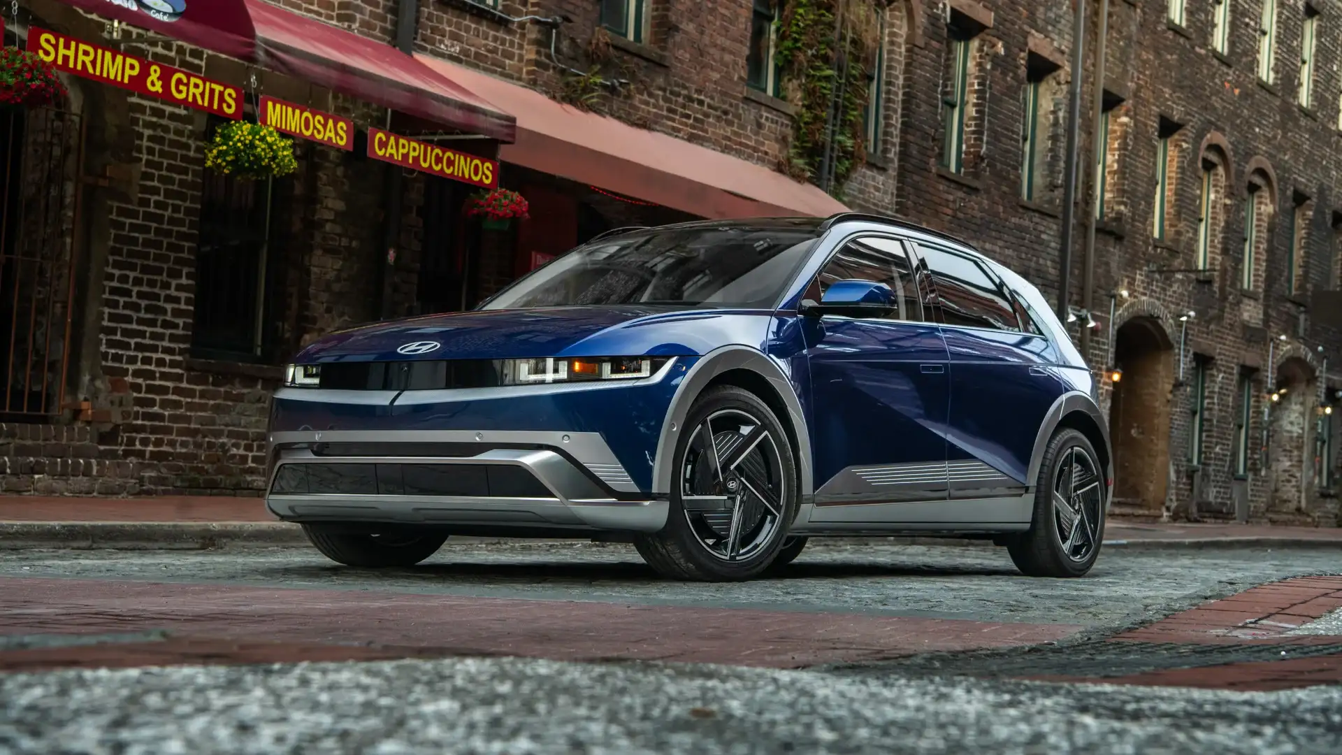 2026 Hyundai IONIQ 5 blue electric SUV parked on city street near brick storefronts.