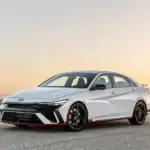 2026 Hyundai Elantra N white sport sedan parked on desert road at sunset with black wheels and red trim.