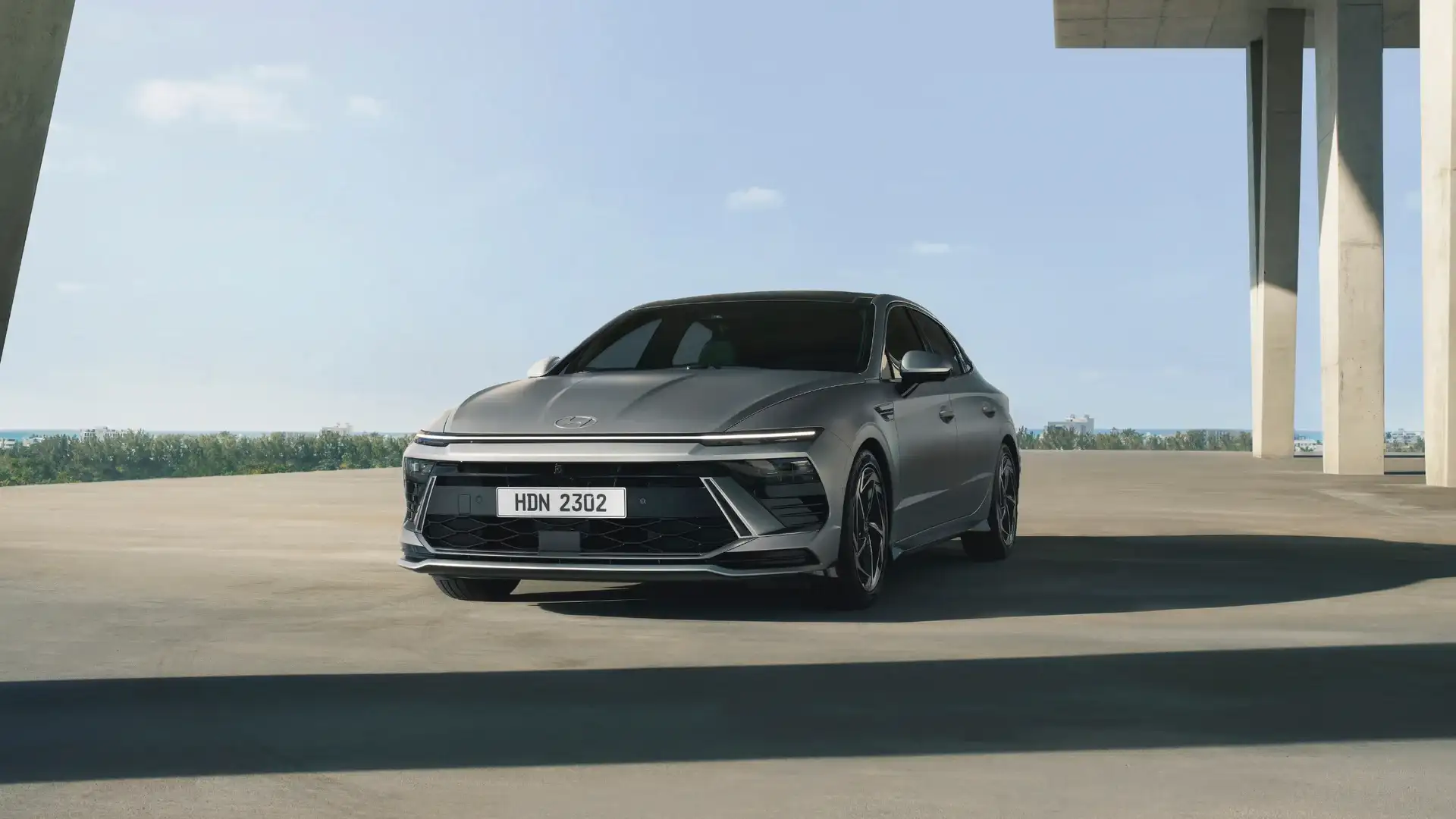 2026 Hyundai Sonata gray sedan parked under modern concrete structure with slim LED front lighting.