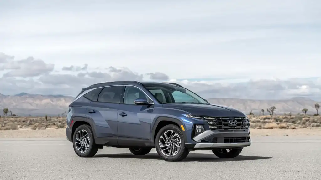2026 Hyundai Tucson blue SUV parked in desert setting with mountain backdrop and bold front grille.