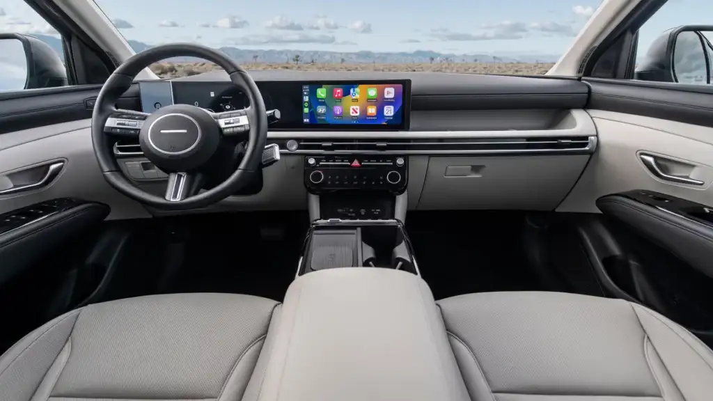 2026 Hyundai Tucson dashboard with wide digital screen, light interior trim, and center console.