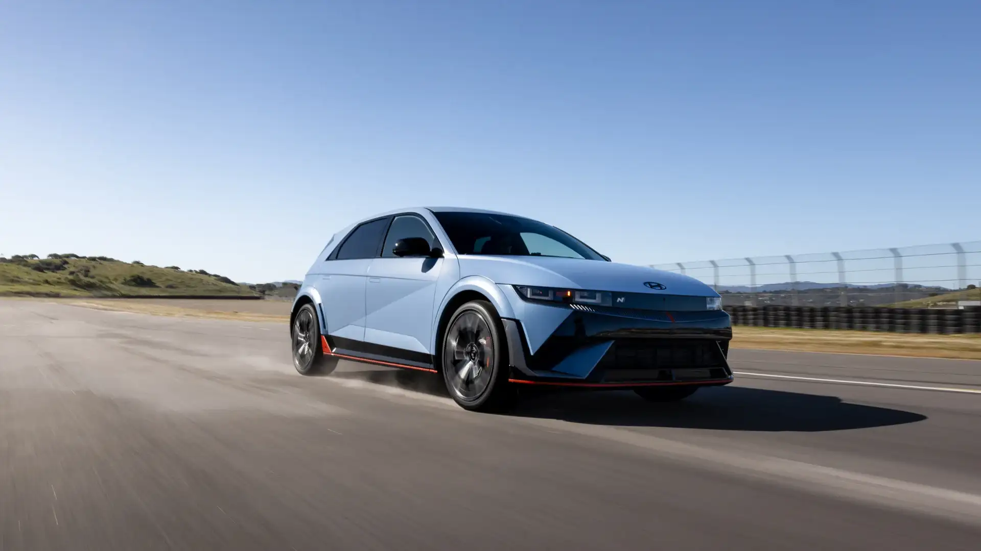 2026 Hyundai IONIQ 5 N blue electric SUV driving on racetrack with black wheels and red trim.