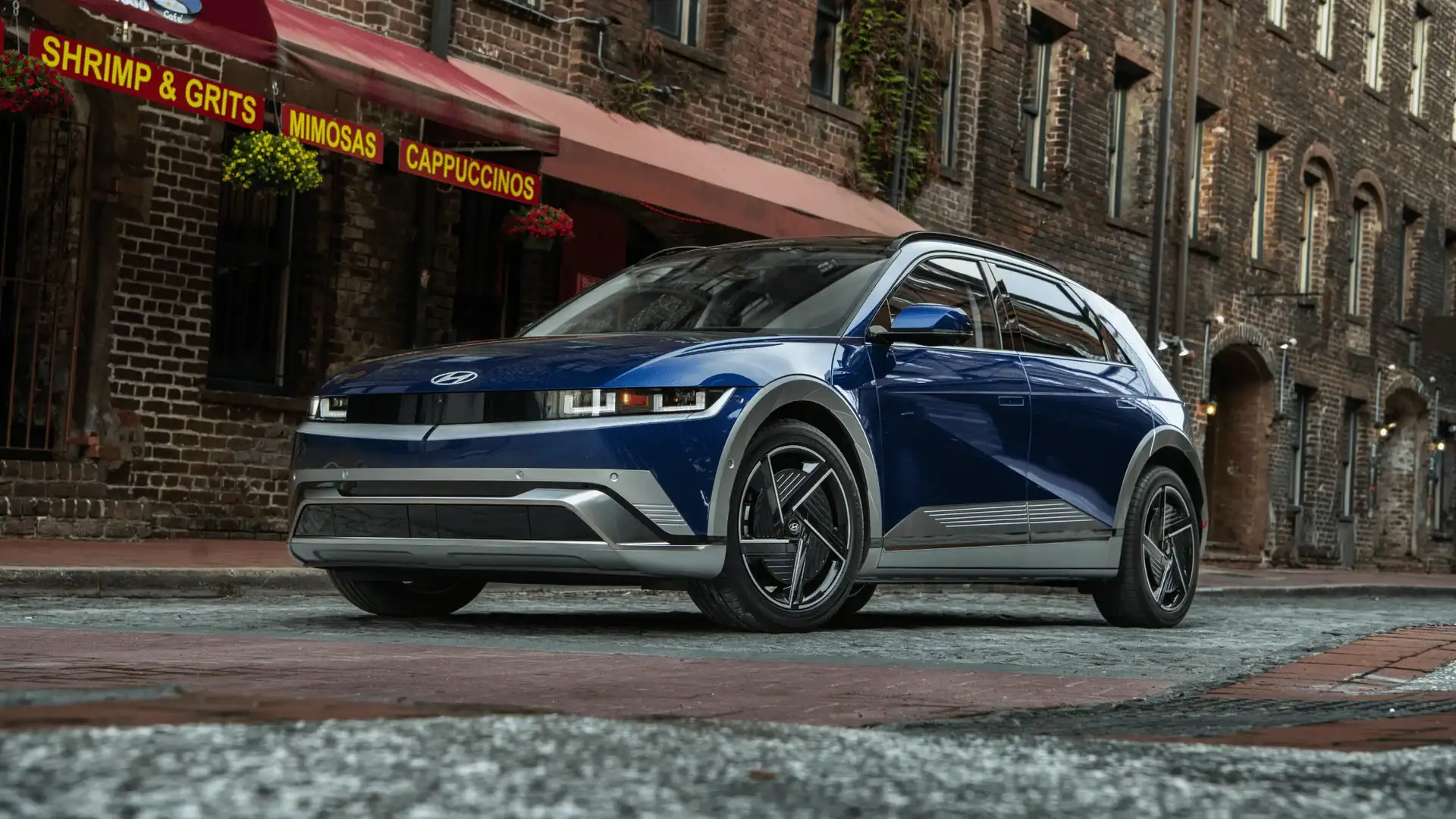 2026 Hyundai IONIQ 5 blue electric SUV parked on city street with brick buildings.