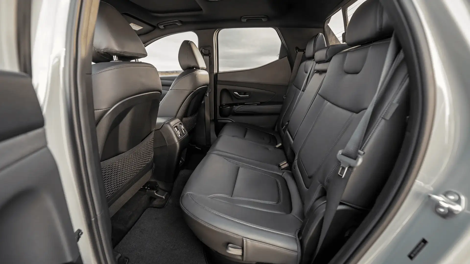 2026 Hyundai Santa Cruz rear cabin with black leather seats, seatbelts, and rear air vents.
