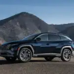 2026 Hyundai Tucson Hybrid black SUV parked roadside with mountain hills in the background.