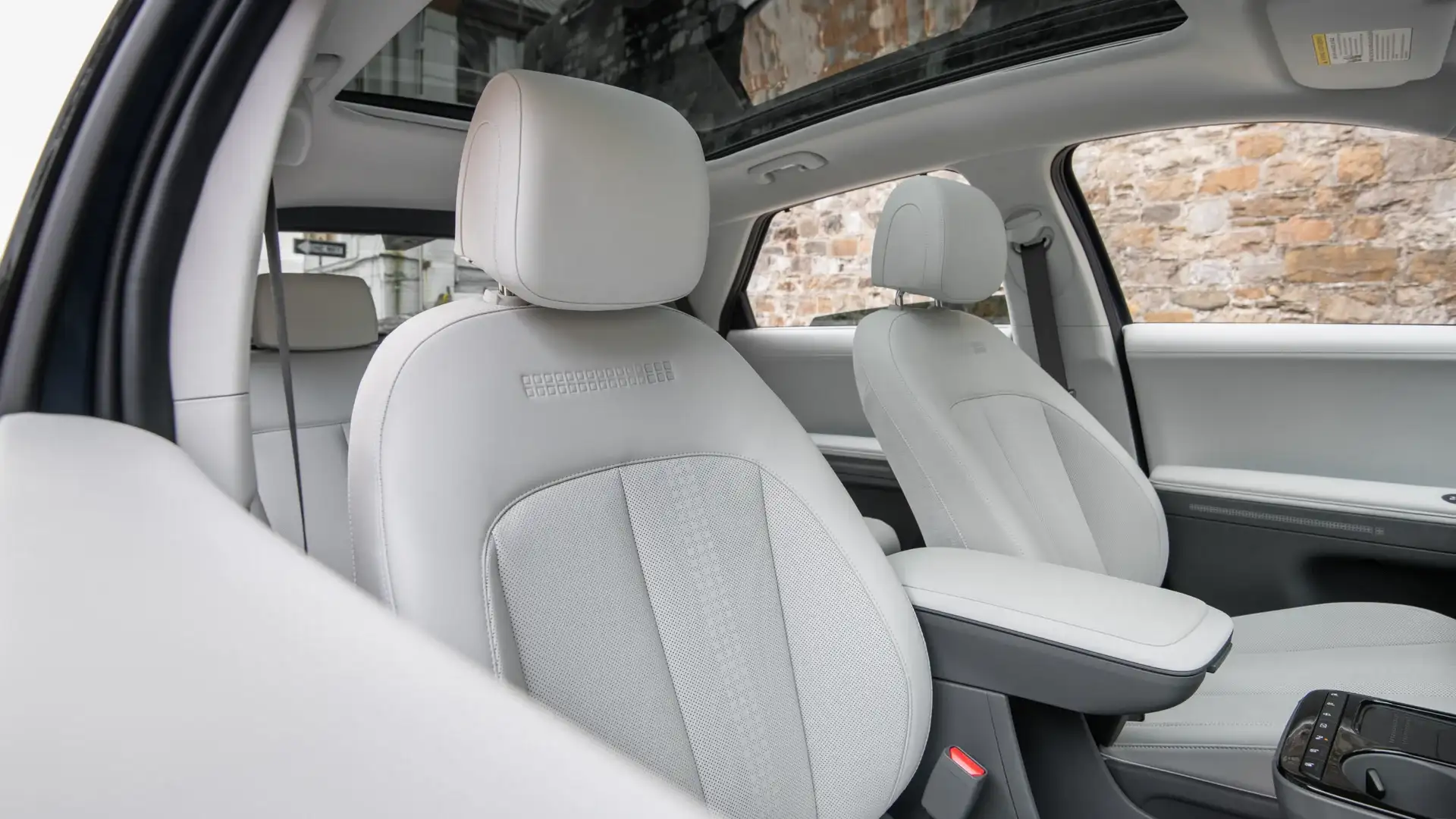 2027 Hyundai IONIQ 5 front cabin with white seats, panoramic roof, and center armrest.
