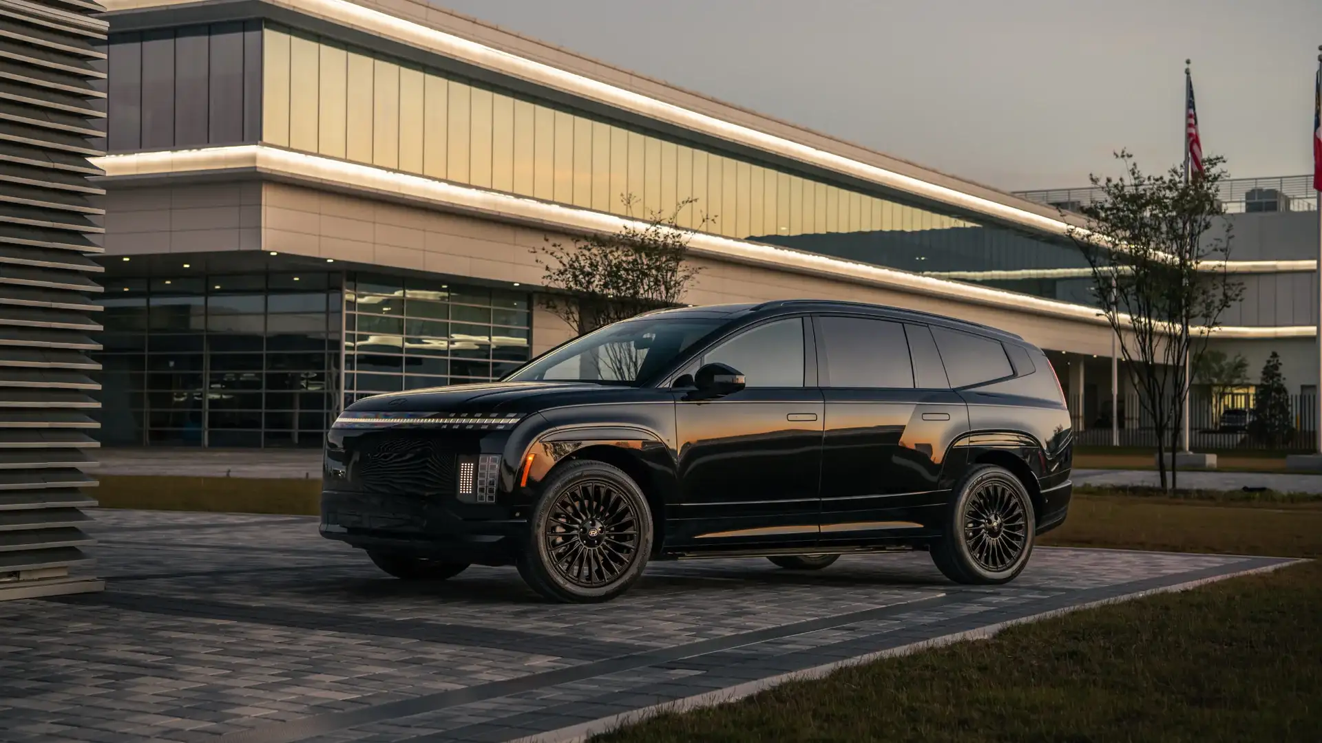 2027 Hyundai IONIQ 9 black electric SUV parked outside a modern building at sunset.