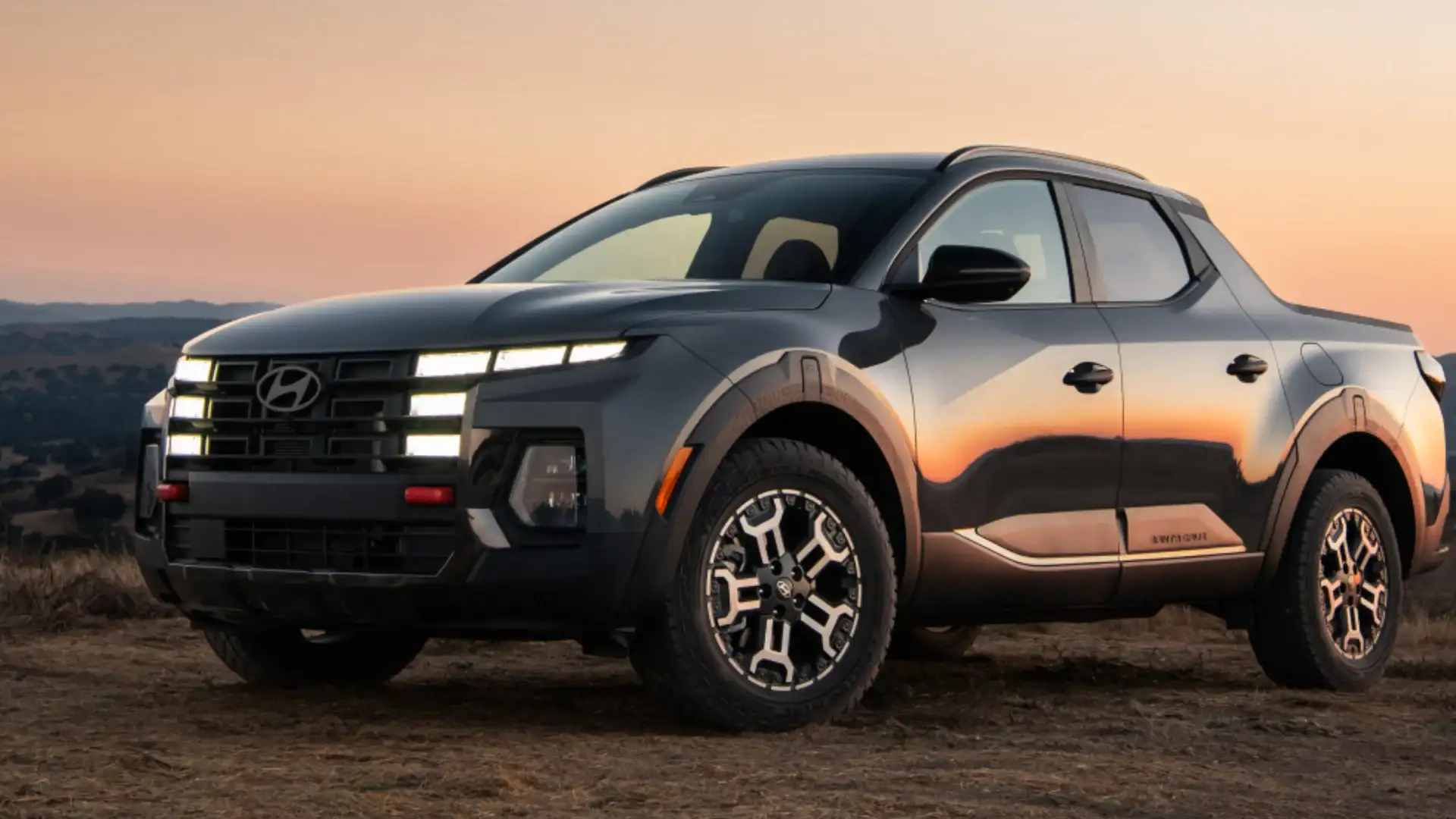 2027 Hyundai Santa Cruz pickup shown at sunset with rugged wheels and modern front lighting.
