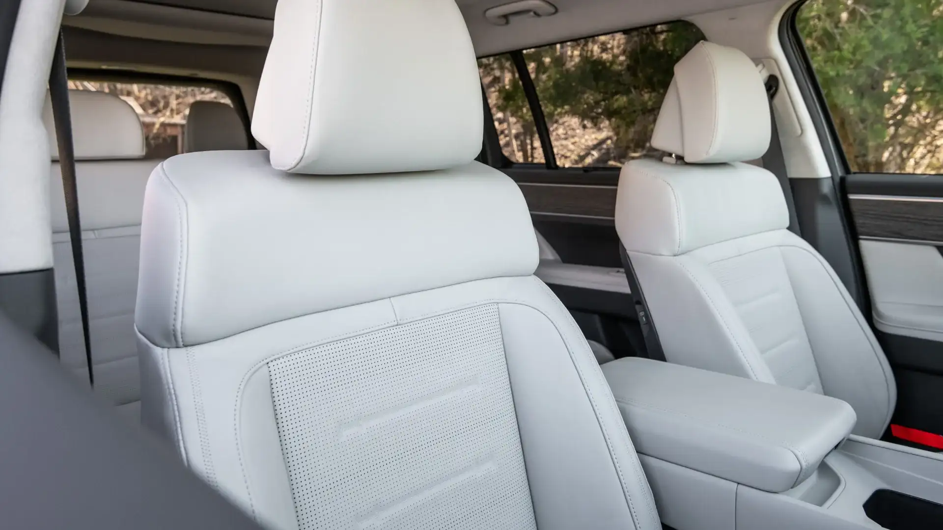 2027 Hyundai Santa Fe front cabin with white seats, center armrest, and textured door trim.