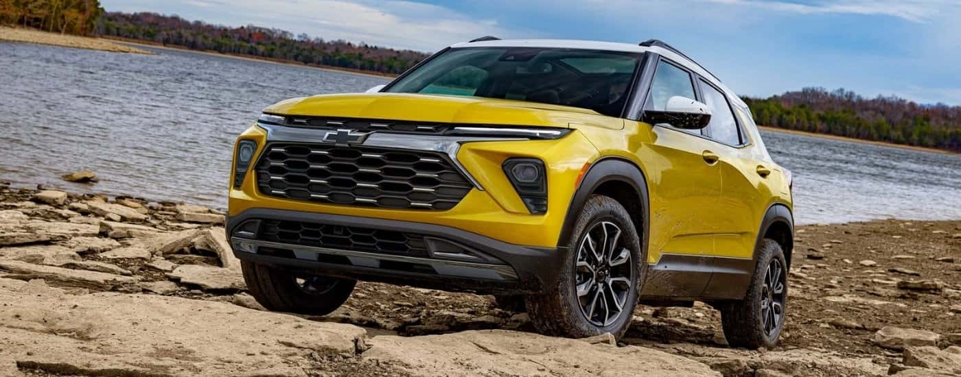 A yellow 2025 Chevy Trailblazer is parked on a lakeshore.