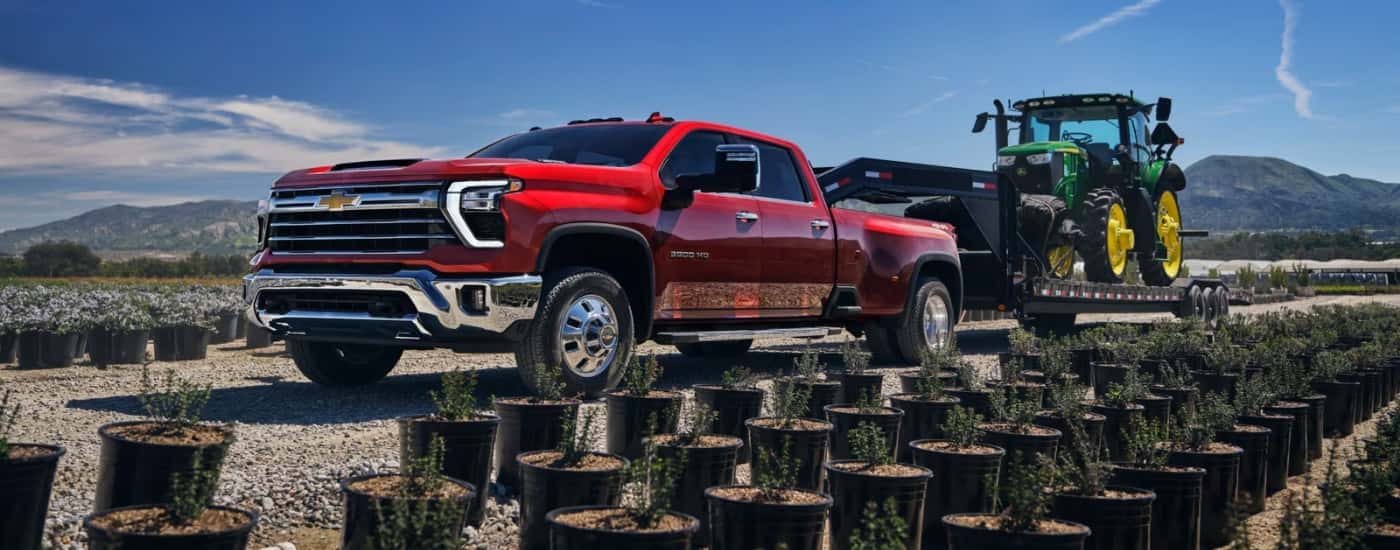 A red 2025 Chevy Silverado 3500 HD is towing a track to a Chevy dealer near Derry.