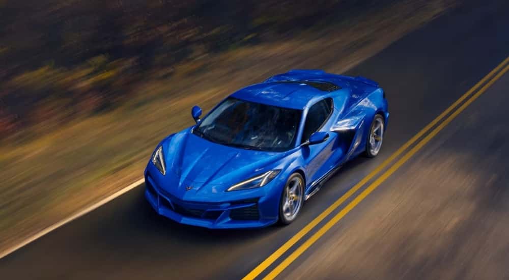 A blue 2025 Chevy Corvette E-Ray driving on an open road.