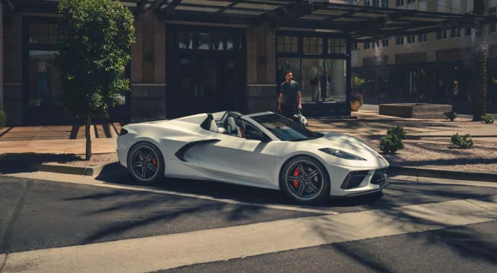 A white 2025 Chevy Corvette for sale in front of a clothing shop.