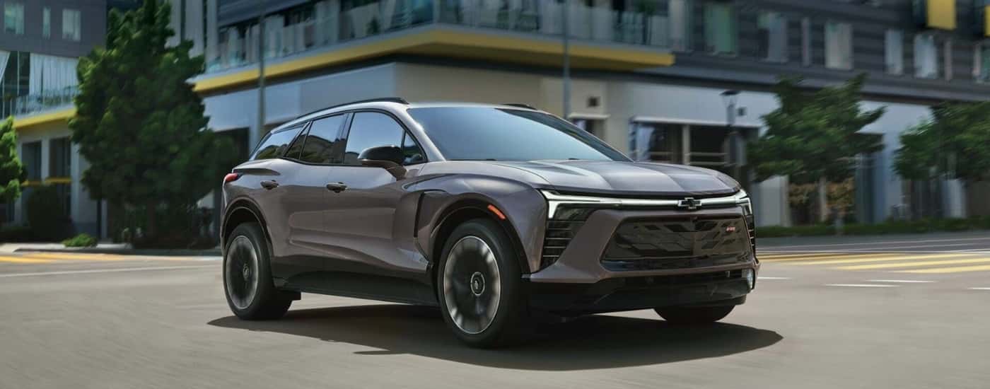 A grey 2025 Chevy Blazer EV RS for sale is driving through an intersection.