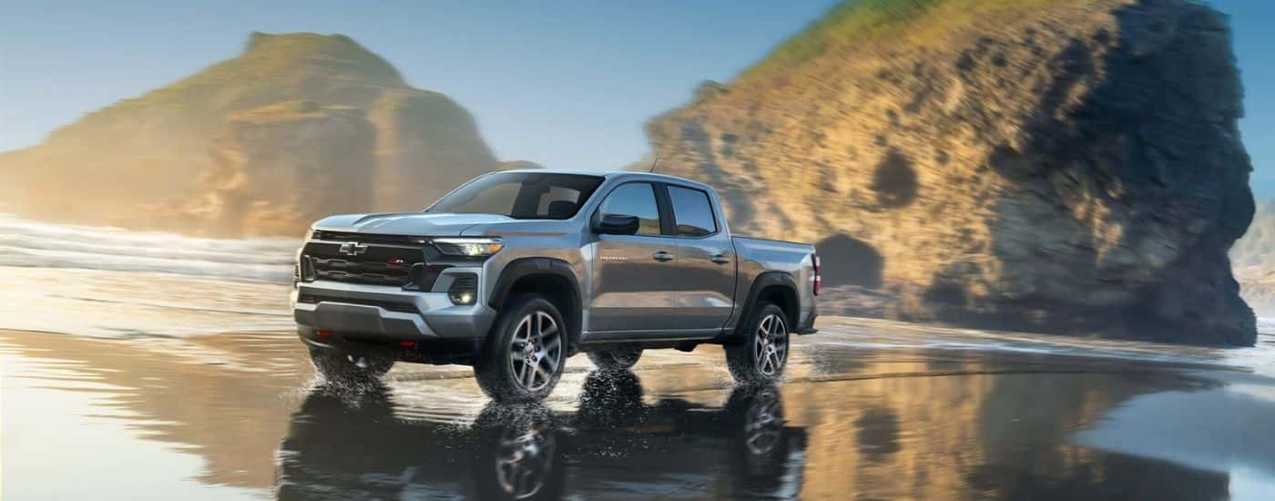 A silver 2023 Chevy Colorado Z71 is shown driving on a beach after leaving a Chevy dealer.