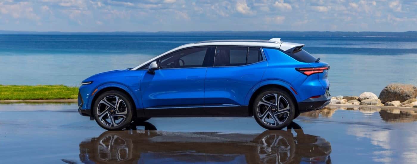 A blue 2024 Chevy Equinox EV parked on wet pavement.