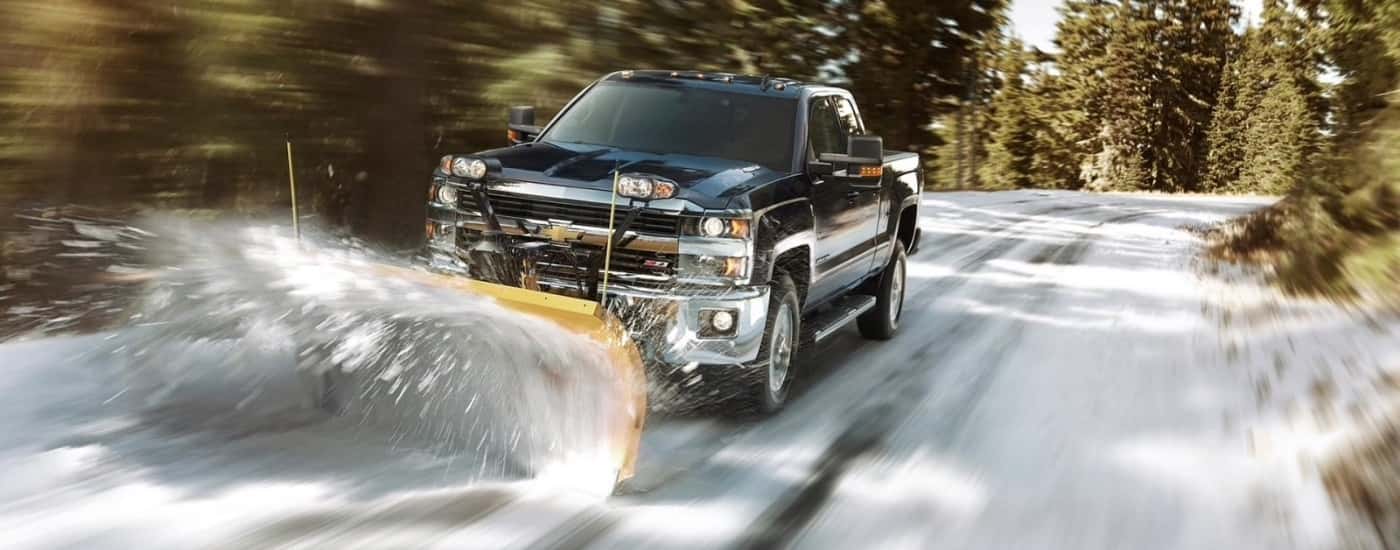 A black 2016 Chevy Silverado 2500 HD Z71 is shown plowing snow.