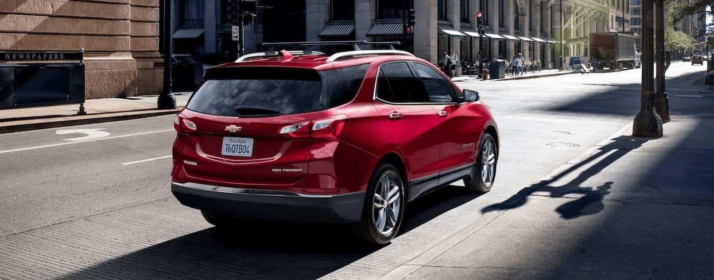 A red 2021 Chevy Equinox is driving on a city street after leaving a used car dealer in Amesbury.