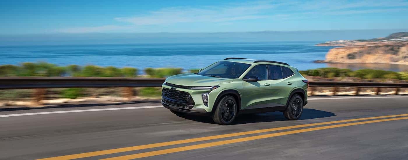 A green 2025 Chevy Trax driving down a highway