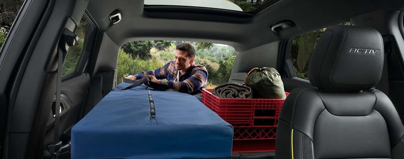 A person storing gear in the black cargo area of a 2025 Chevy Trailblazer ACTIV.
